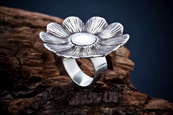 Anillo de plata con diseño de flor en fotografía de alta calidad sobre fondo rústico