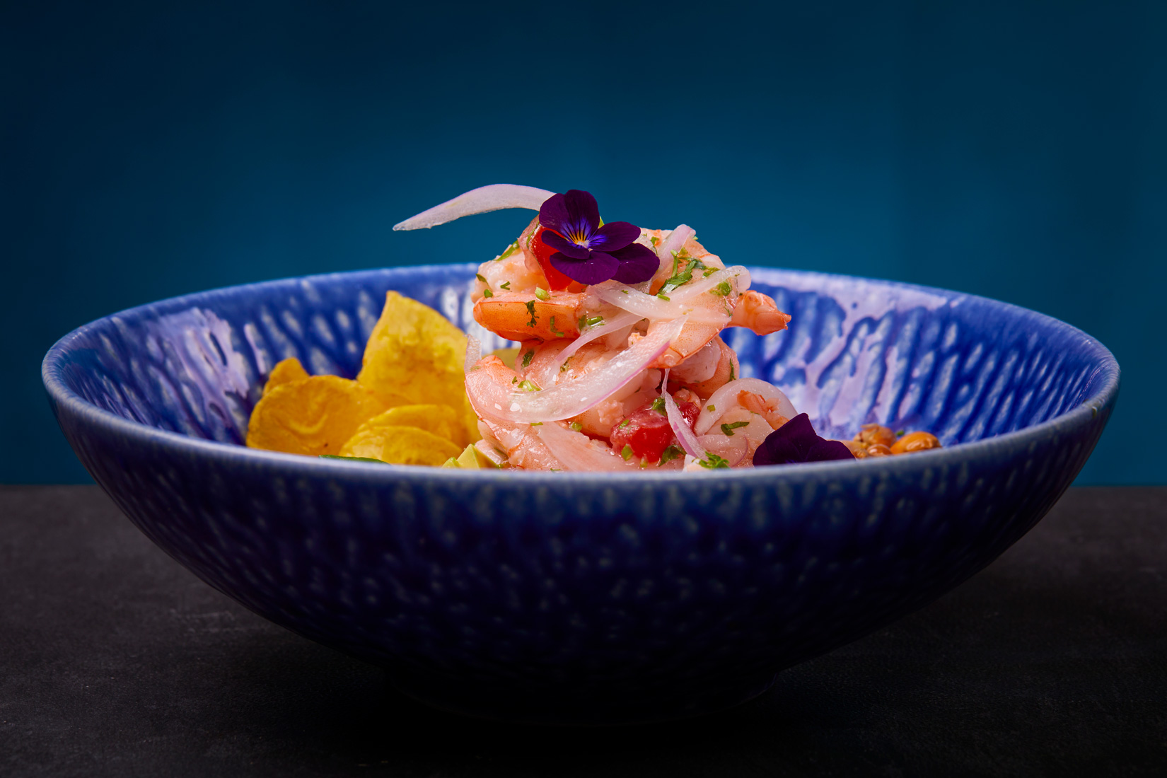 Fotografía profesional de un ceviche servido en un bowl azul con detalles decorativos, realizada por NUA Estudio.