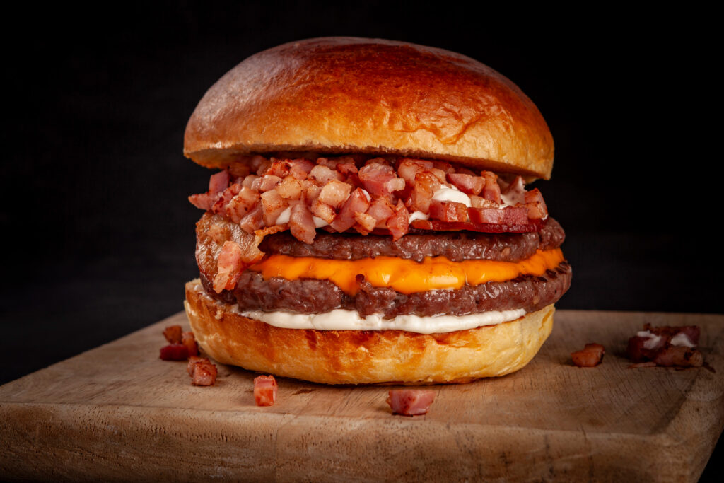 Fotografía gastronómica para Iulius, destacando sus hamburguesas con una iluminación y encuadre que realzan su textura y presentación. Imágenes pensadas para menús, redes sociales y campañas publicitarias. Si necesitas fotografías de calidad para tu negocio gastronómico, contáctanos.