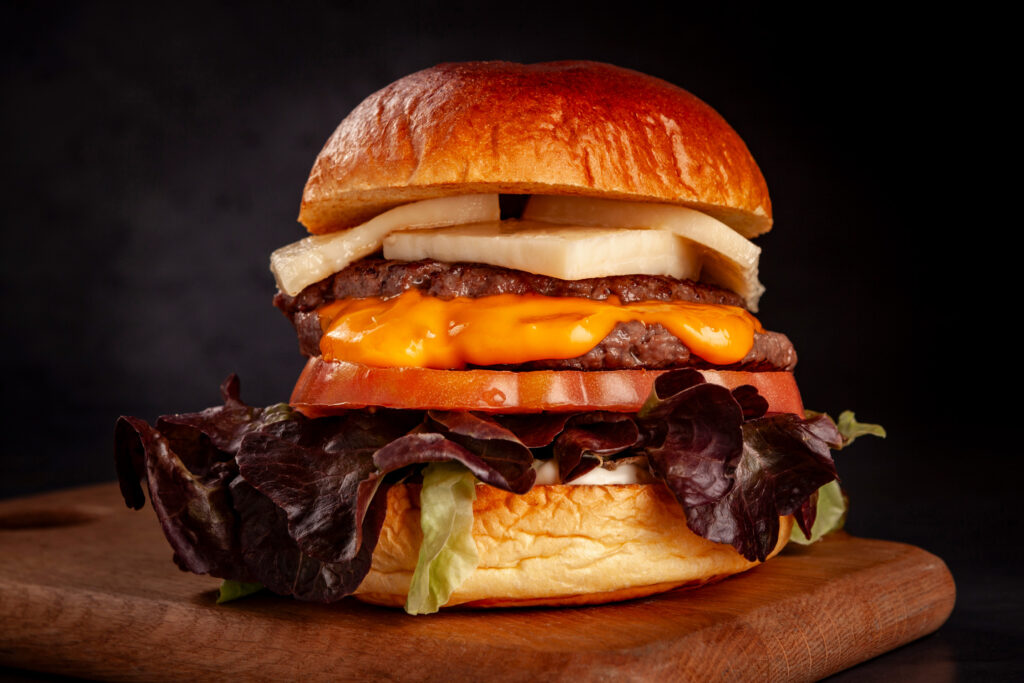 Fotografía gastronómica para Iulius, destacando sus hamburguesas con una iluminación y encuadre que realzan su textura y presentación. Imágenes pensadas para menús, redes sociales y campañas publicitarias. Si necesitas fotografías de calidad para tu negocio gastronómico, contáctanos.